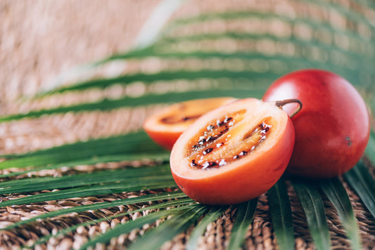 Tamarillo fruit or terong belanda with palm leaves on rattan background. Copy space. Tropical travel